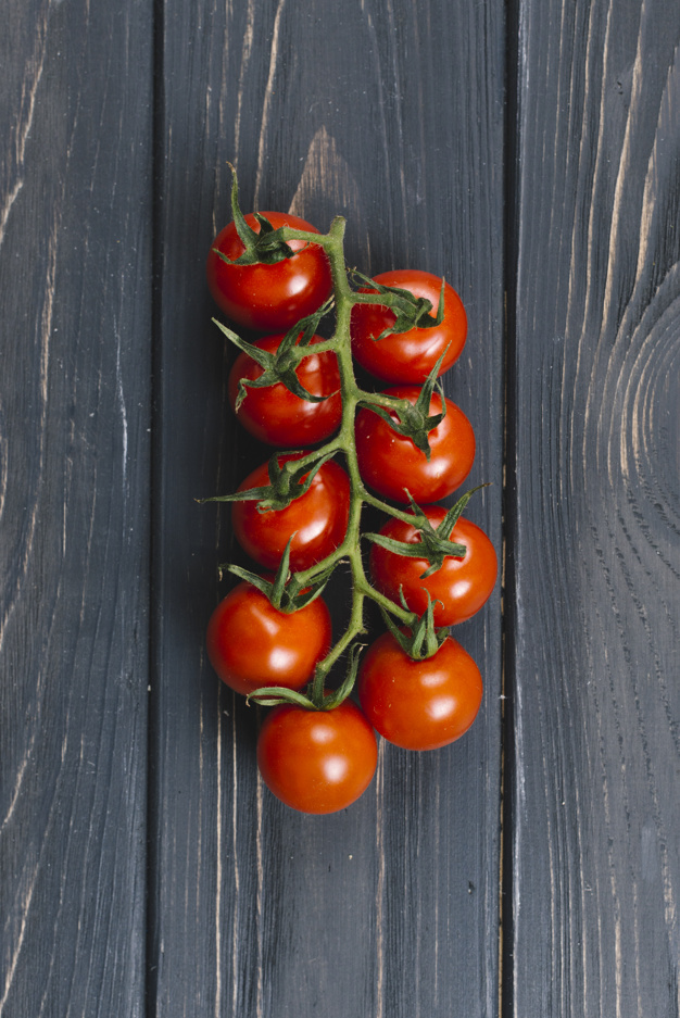 ripe fresh cherry tomatoes on branch against black wooden plank 23 2148062432
